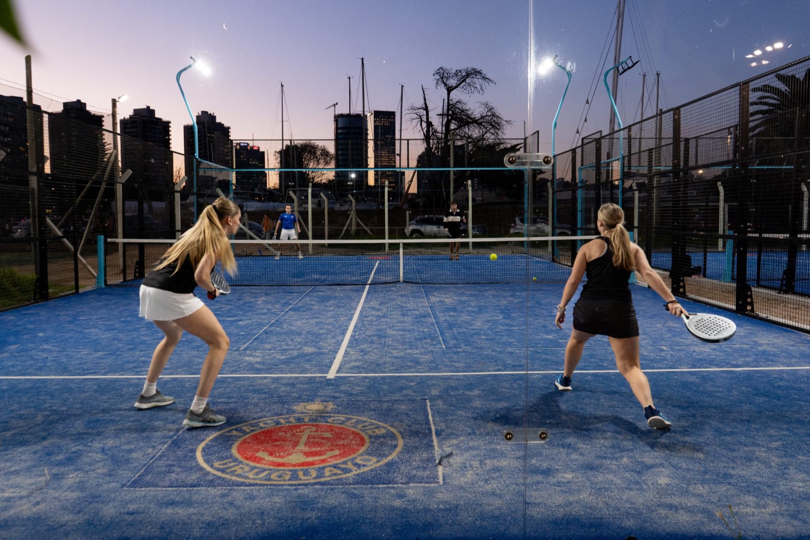 Socias jugando pádel en las canchas del Yacht Club Uruguayo al atardecer